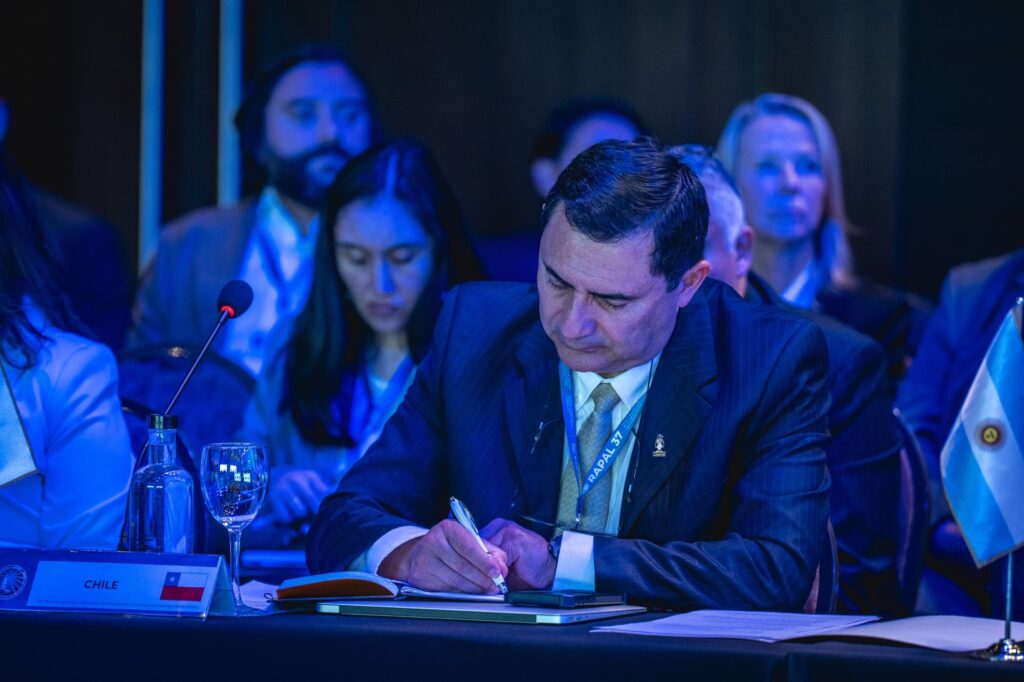 Un delegado de Chile toma notas en la sala plenaria, junto al cartel de su país