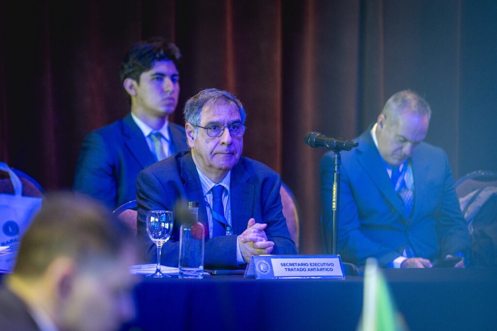 El secretario ejecutivo del Tratado Antártico sentado en su lugar de la sala plenaria, con las manos cruzadas