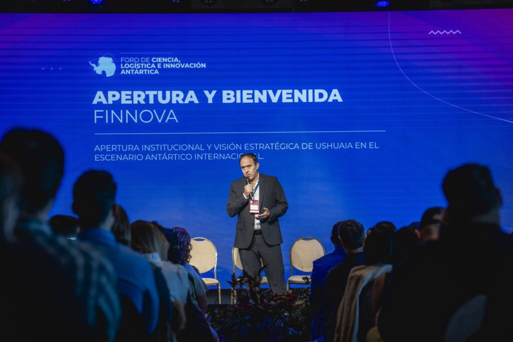 Presidente de FINNOVA en la apertura del Foro, hablando por micrófono frente a la pantalla de Apertura y Bienvenida