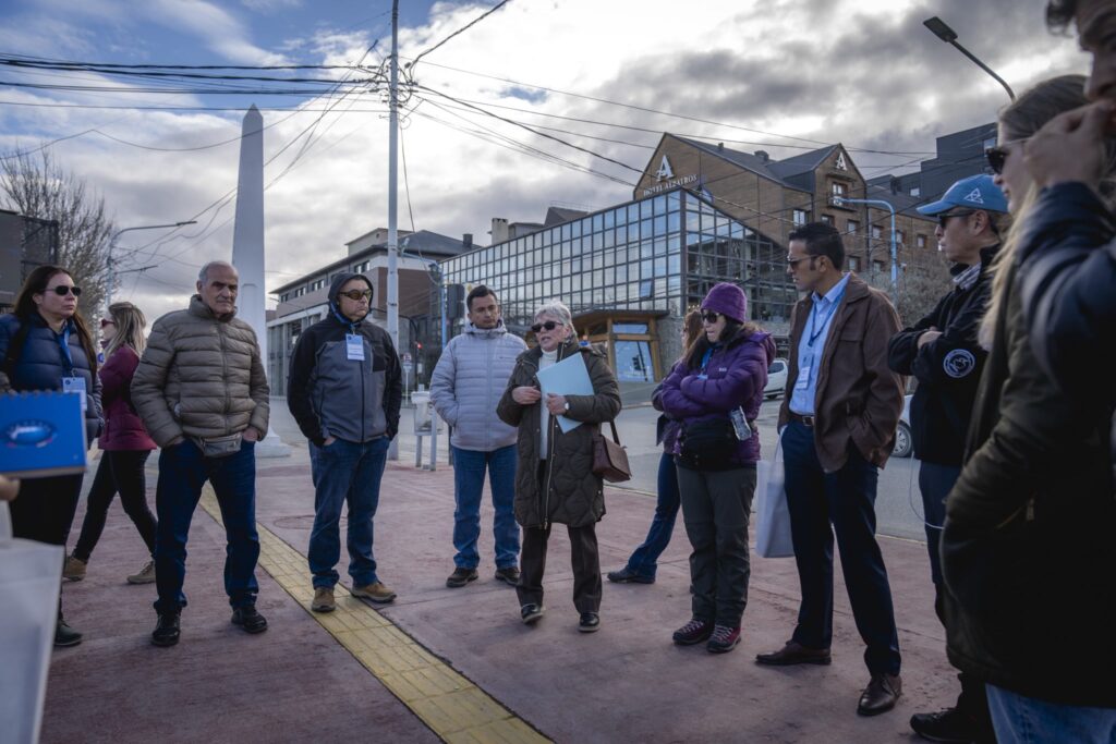 Delegados con credenciales escuchan a una guía durante el recorrido terrestre por el centro de Ushuaia
